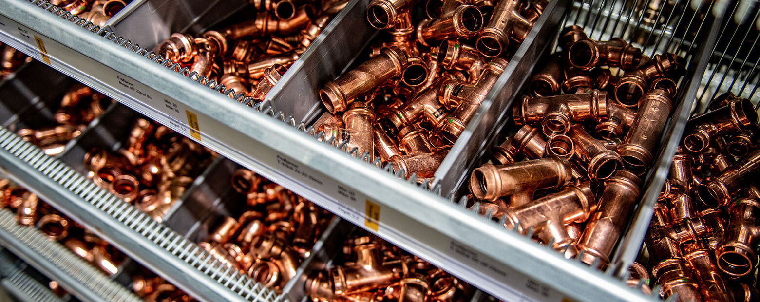 Lagerregal mit sortierten Kupferrohr-Fittings und Rohrverbindern in verschiedenen Größen und Formen.