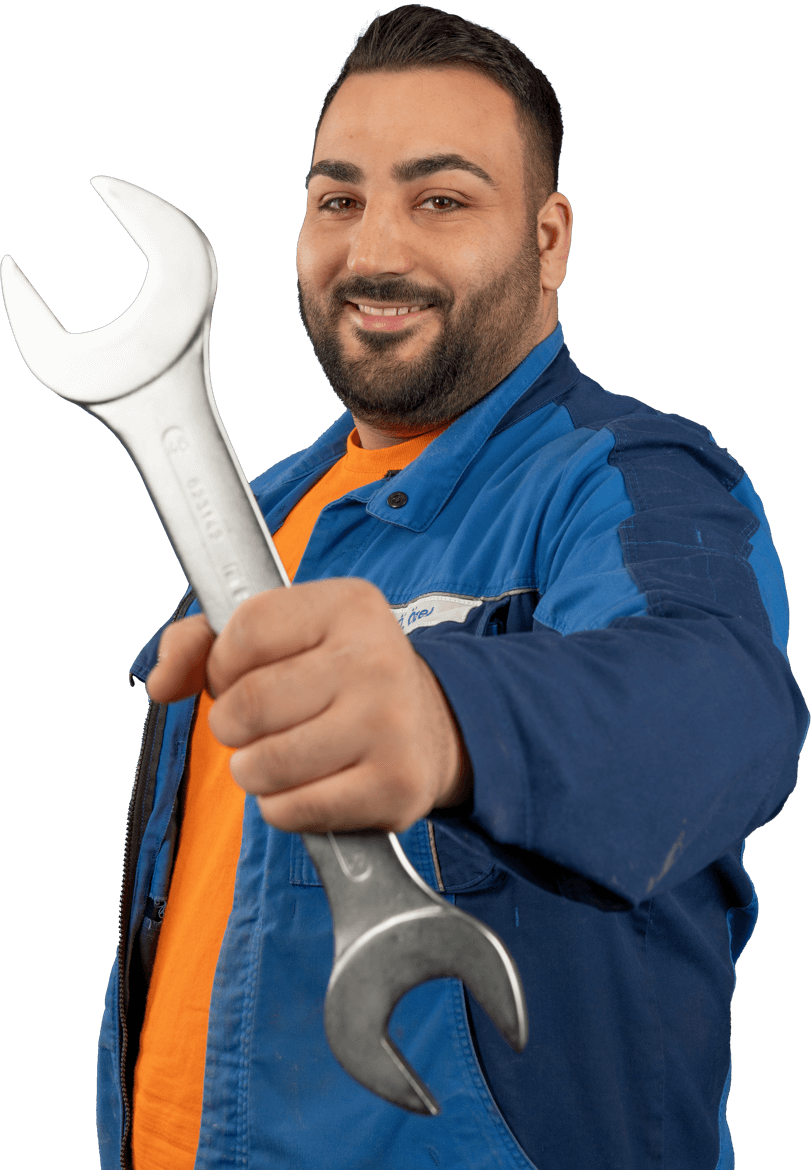 Mitarbeiter in blauer Arbeitskleidung und orangefarbenem Shirt hält einen großen Schraubenschlüssel nach vorne.