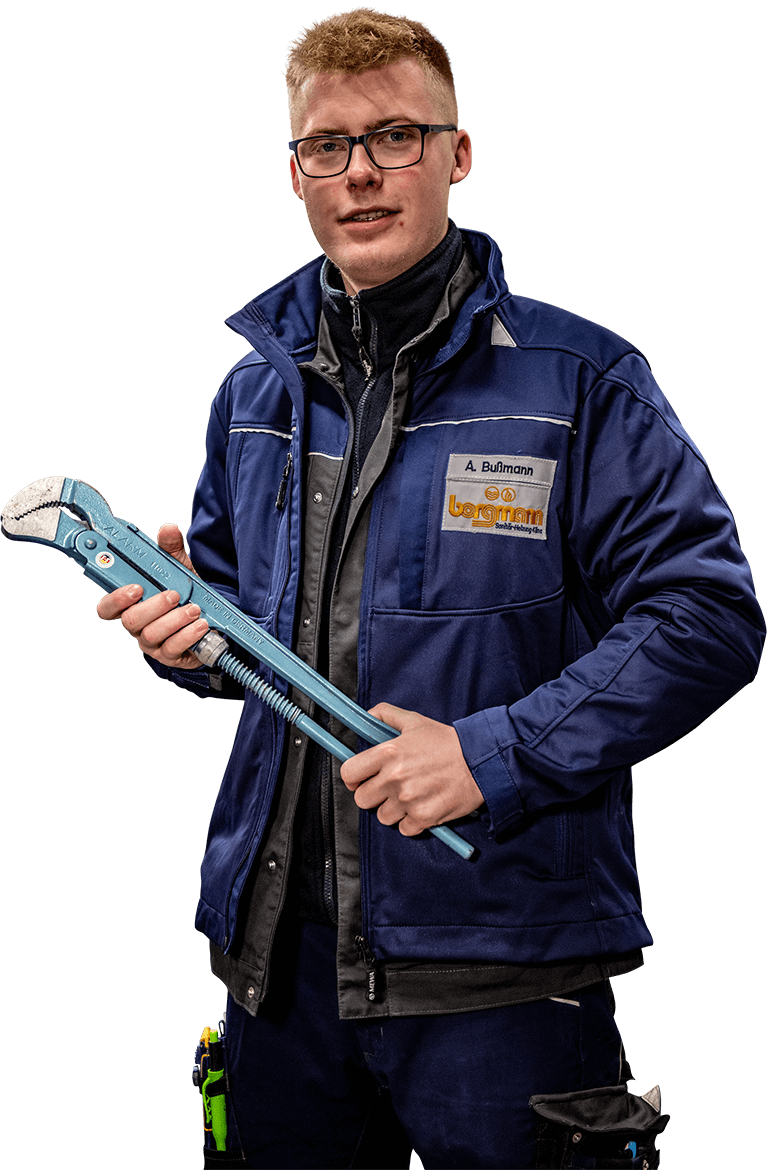 Mitarbeiter in blauer Arbeitskleidung hält eine große Rohrzange in den Händen, Namensschild 'A. Bußmann' sichtbar.